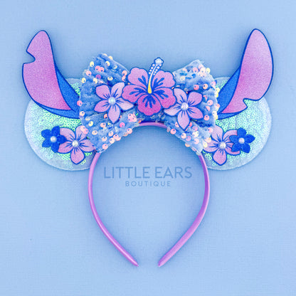 Decorative headband with floral design and 'Little Ears Boutique' branding on a light blue background